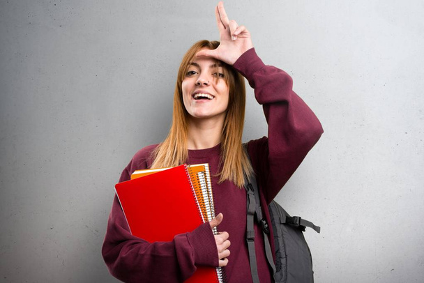 Student woman making loser sign on grey background - Photo, Image
