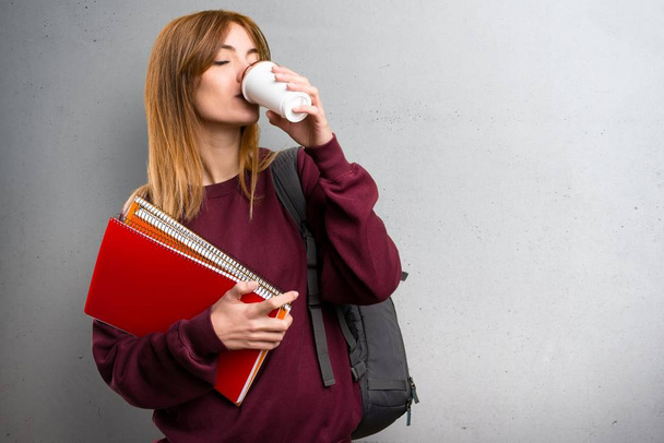 Student vrouw met een kopje koffie op een grijze achtergrond - Foto, afbeelding