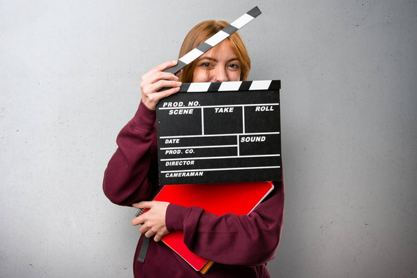 Student vrouw met een Filmklapper op grijze achtergrond - Foto, afbeelding