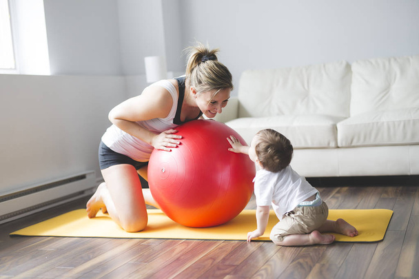 sports mother is engaged in fitness and yoga with a baby at home - Photo, image