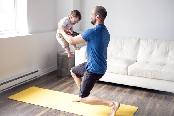 hombre deportivo se dedica a la aptitud y el yoga con un bebé en casa
 - Foto, imagen