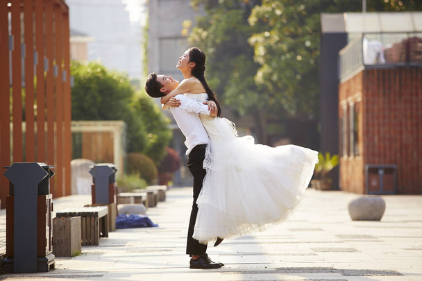 азіатська наречена і наречена обіймає на відкритому повітрі
 - Фото, зображення