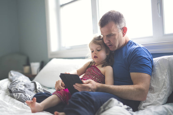 father and daughter relax in bed with tablet computer - Φωτογραφία, εικόνα