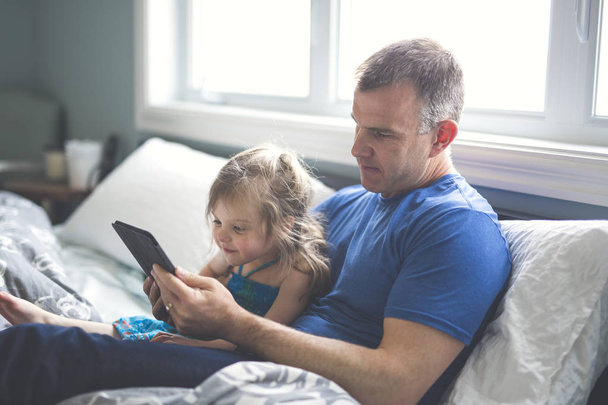 Ojciec i córka się zrelaksować w łóżku z komputera typu tablet - Zdjęcie, obraz