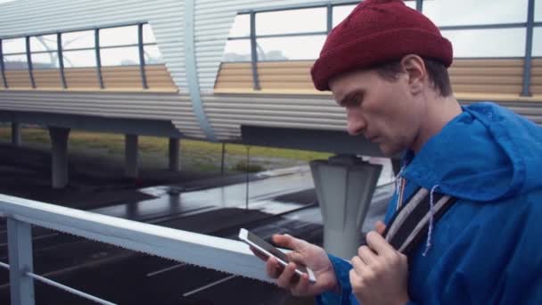 Fiatal természetjáró használ smartphone folyamatos közúti híd. Út-autópálya háttér - Felvétel, videó