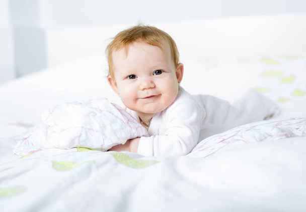 Portrait of a crawling baby on the bed in her room - Foto, afbeelding