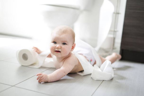 Toddler ripping up toilet paper in bathroom - Foto, afbeelding