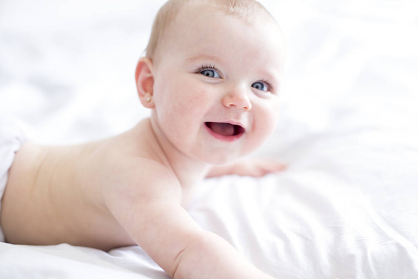 Baby girl in white bedding at home look nice - Fotografie, Obrázek
