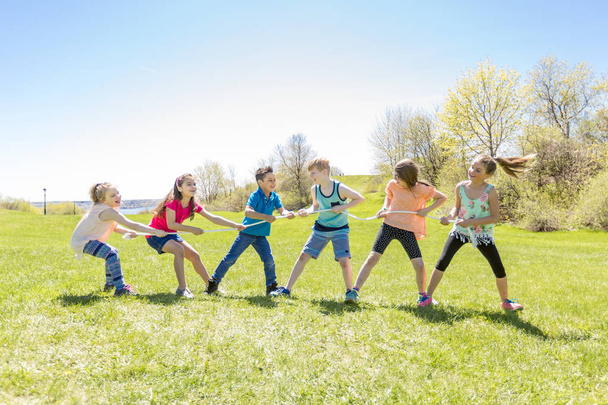 Grupo de criança se divertir em um campo com corda
 - Foto, Imagem