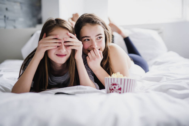 teenage girls eating popcorn and watching horror movie on tv at home - Zdjęcie, obraz