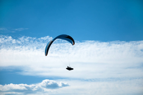 Parapente volando en el cielo azul sobre el fondo de las nubes
. - Foto, imagen