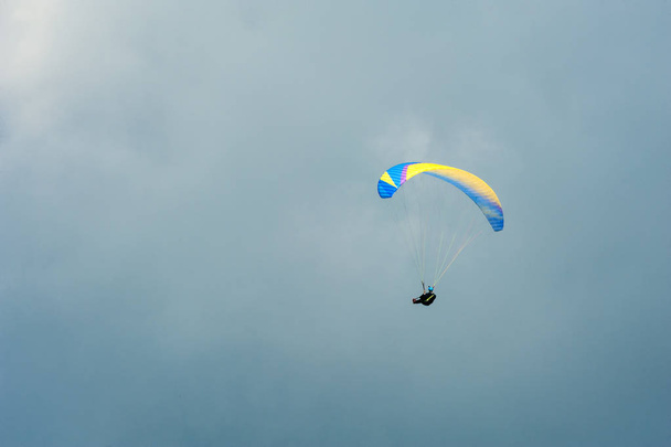 Parapente volando en el cielo azul sobre el fondo de las nubes
. - Foto, imagen
