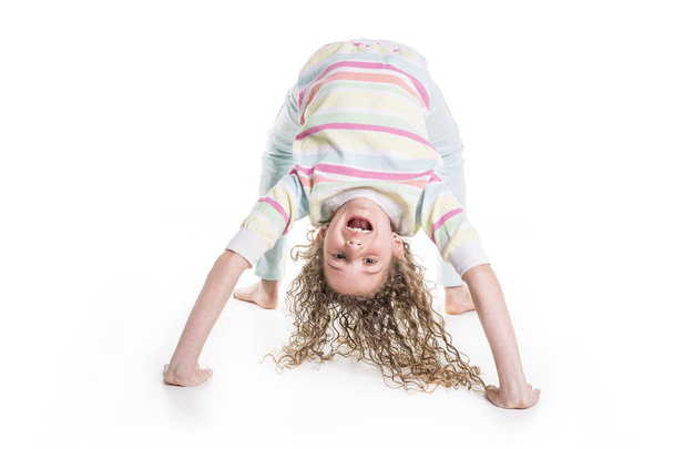Portrait of happy, smiling, confident 9 years old girl with curly hair, isolated on white upside down - Photo, Image