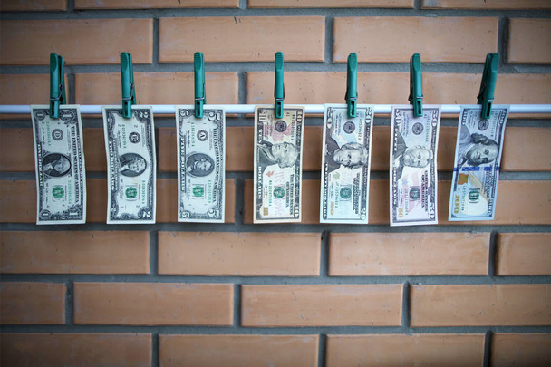 Rahanpesun käsite - dollarit kuivuvat sorvin päällä tiiliseinällä taustalla
 - Valokuva, kuva