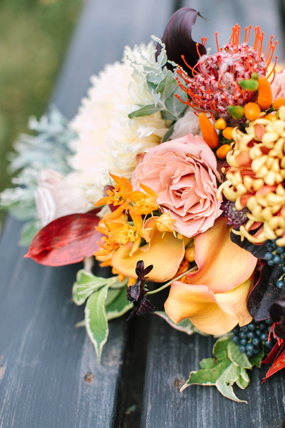 flower arranging, surprise, decoration concept. there is all coloures of the rainbow and all their shades in one graceful wedding bouquet that placed on the black bench - Zdjęcie, obraz