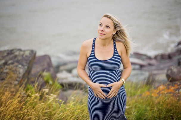 Portrait of a young beautiful blond pregnant woman on the side of the beach - Foto, imagen