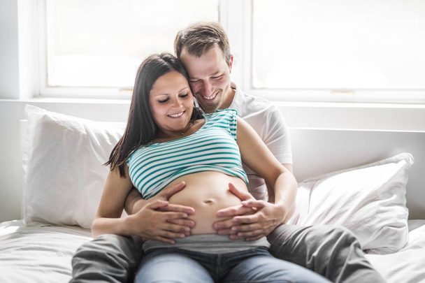Young parents in bed expecting a little baby, Romantic moments for pregnant couple - Foto, Bild