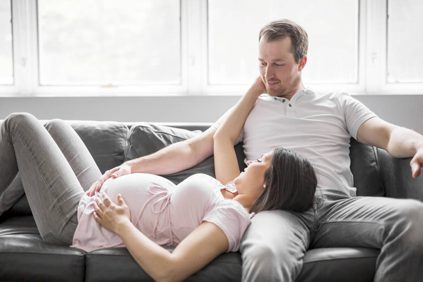 Couple With Pregnant Woman Relaxing On Sofa Together - Foto, immagini