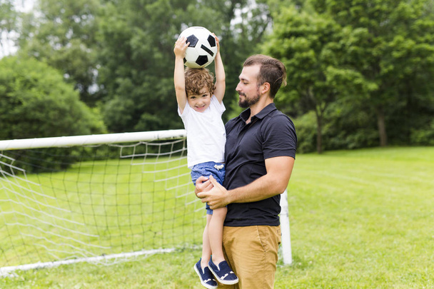 père avec fils jouant au football sur le terrain de football
 - Photo, image