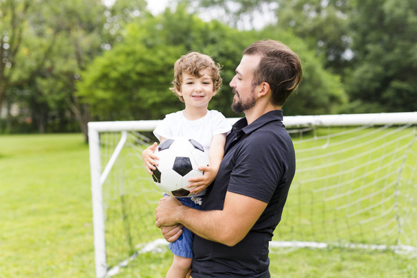 father with son playing football on football pitch - Photo, image
