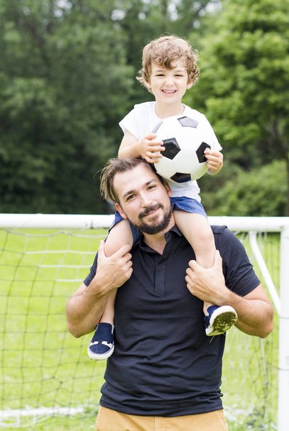 father with son playing football on football pitch - Photo, image