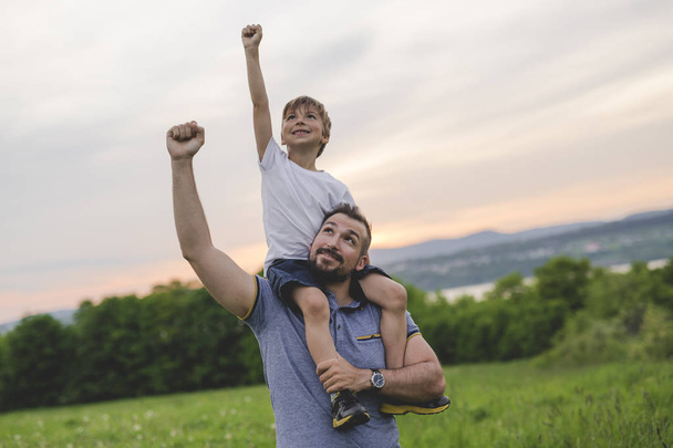 Father and son having fun outdoors in the meadow - Foto, immagini