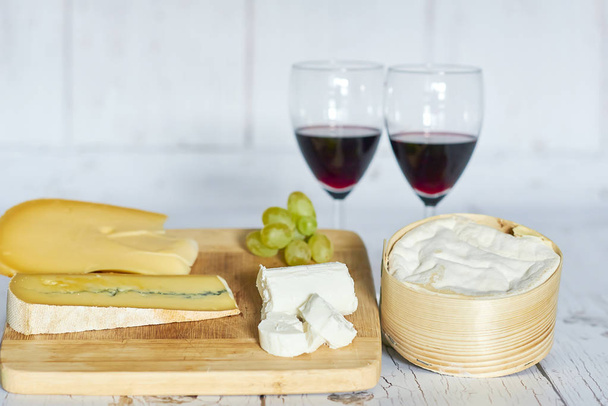 Two glasses of red wine and cheese board on wooden tray - horizontal - Photo, Image