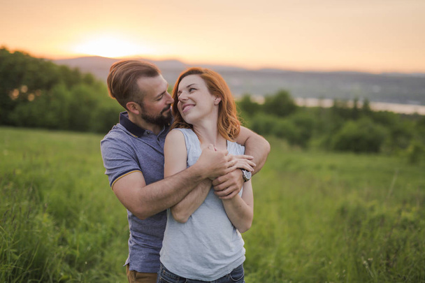 Young couple enjoying the sunset in the meadow - Photo, Image