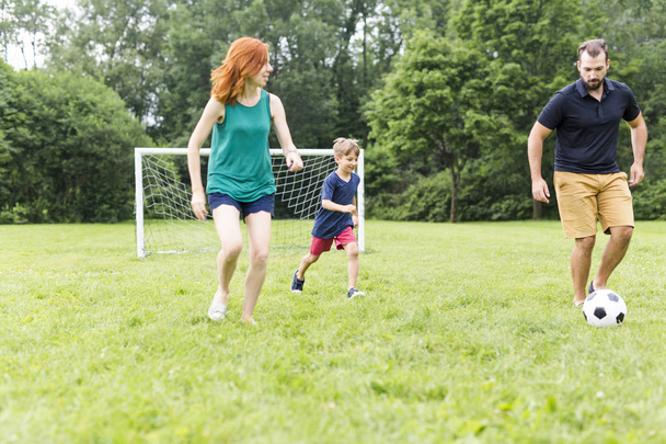 Cheerful family playing football in a park - Photo, image