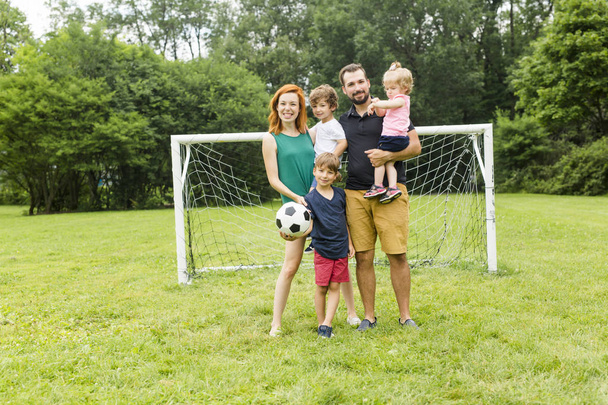 Щаслива сім'я з футбольним м'ячем на полі
 - Фото, зображення