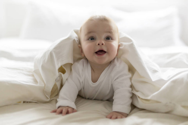 Cute happy 7 month baby girl in diaper lying and playing - Foto, imagen