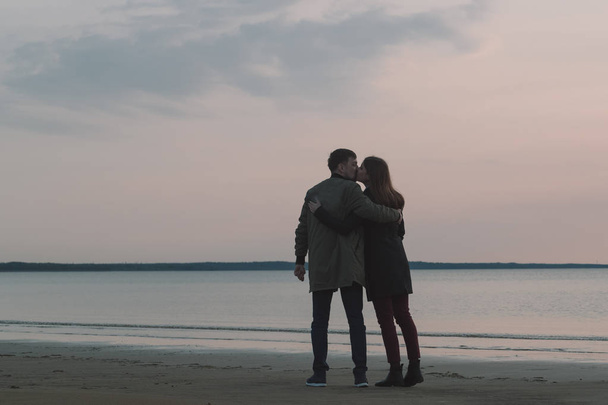 young loving couple kissing on the seashore in autumn. - Fotó, kép