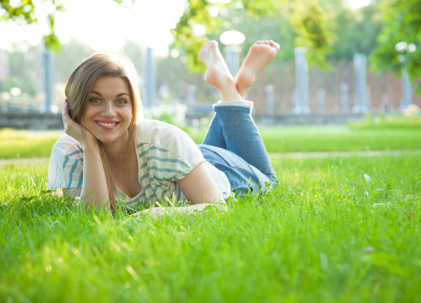 Smiling young woman lying on grass - Fotoğraf, Görsel