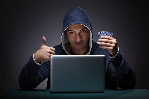 Young man wearing a hoodie sitting in front of a laptop computer - Foto, Imagem