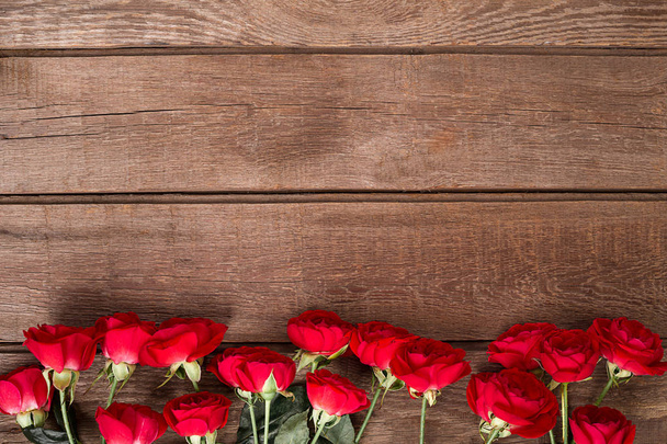 Red roses bouquet over wooden table. Top view with copy space. - Foto, Imagem