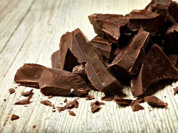 Nahaufnahme von Schokoladenstücken auf hölzernem Hintergrund - Foto, Bild