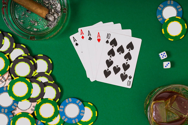 gambling, fortune and entertainment concept - close up of casino chips, whisky glass, playing cards and cigar on green table surface - 写真・画像
