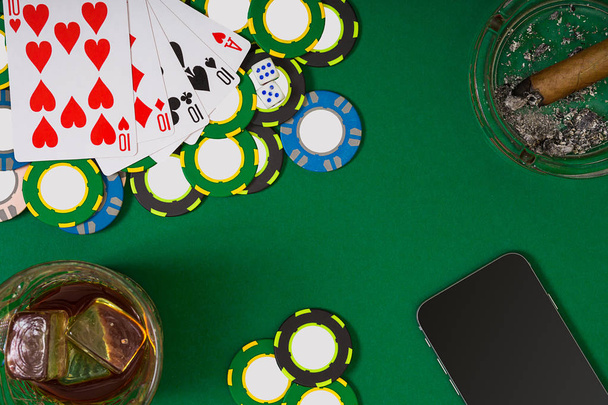 gokken, fortuin en entertainment concept - close-up casinofiches, whisky glas, speelkaarten en sigaar op groene tafel oppervlak - Foto, afbeelding