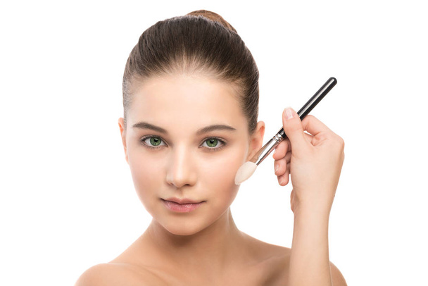 Young brunette woman with clean face. Girl perfect skin applying cosmetic brush. Isolated on a white. - Foto, Imagen
