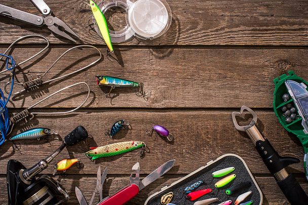 Fishing tackle - fishing spinning, fishing line, hooks and lures on wooden background. - Photo, Image