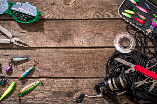 Fishing tackle - fishing spinning, fishing line, hooks and lures on wooden background. - Fotó, kép