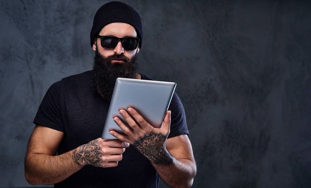 Бородатий жорстокий чоловік тримає планшетний ПК
 - Фото, зображення