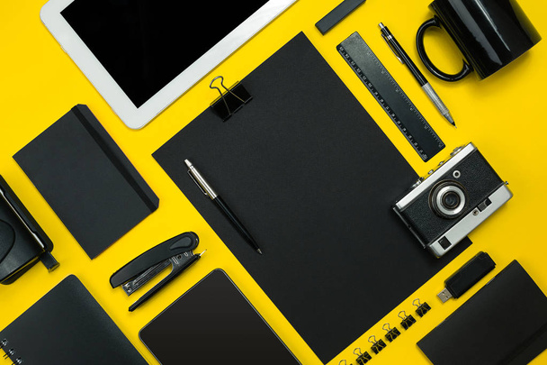 Black objects from the office on a yellow background. Work and creativity. Top view. - Fotoğraf, Görsel