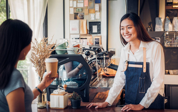Mujer asiática barista usar delantal de jean servido para ir taza de café a
  - Foto, imagen