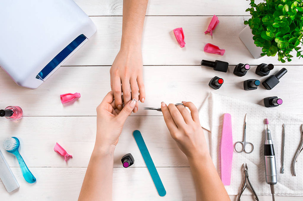 Soins des ongles. Gros plan de mains féminines classant des ongles avec lime à ongles professionnelle dans le salon de beauté. Vue du dessus
 - Photo, image
