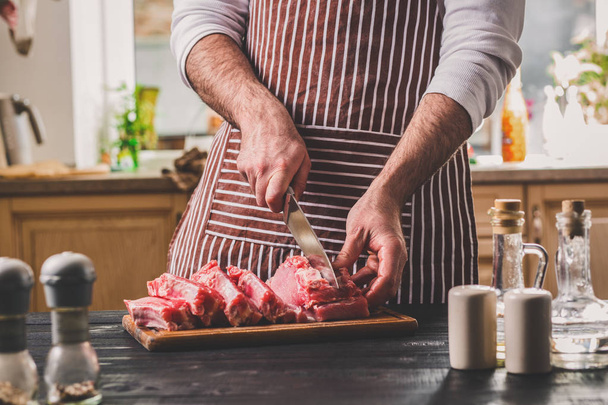 Człowiek kawałki świeże kawałek wołowiny na drewniane deska w kuchni domowej - Zdjęcie, obraz