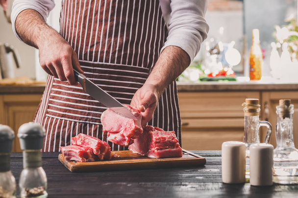Los cortes de hombre de carne fresca en una tabla de cortar de madera en la cocina del hogar
 - Foto, Imagen