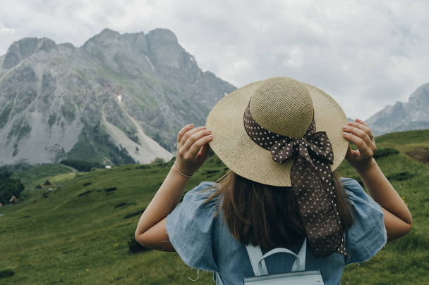 Zpět z žena cestovatele s modrým batoh drží klobouk a vzhled - Fotografie, Obrázek