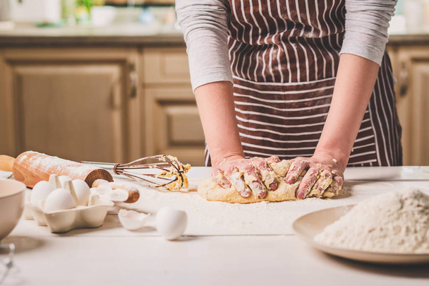 Mains de femme pétrissant la pâte sur la table de cuisine
 - Photo, image