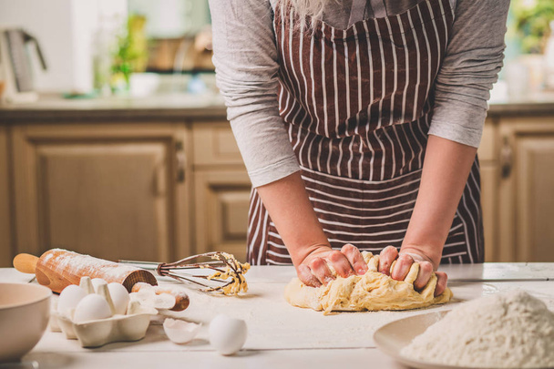 Жінка руки замішує тісто на кухонному столі
 - Фото, зображення